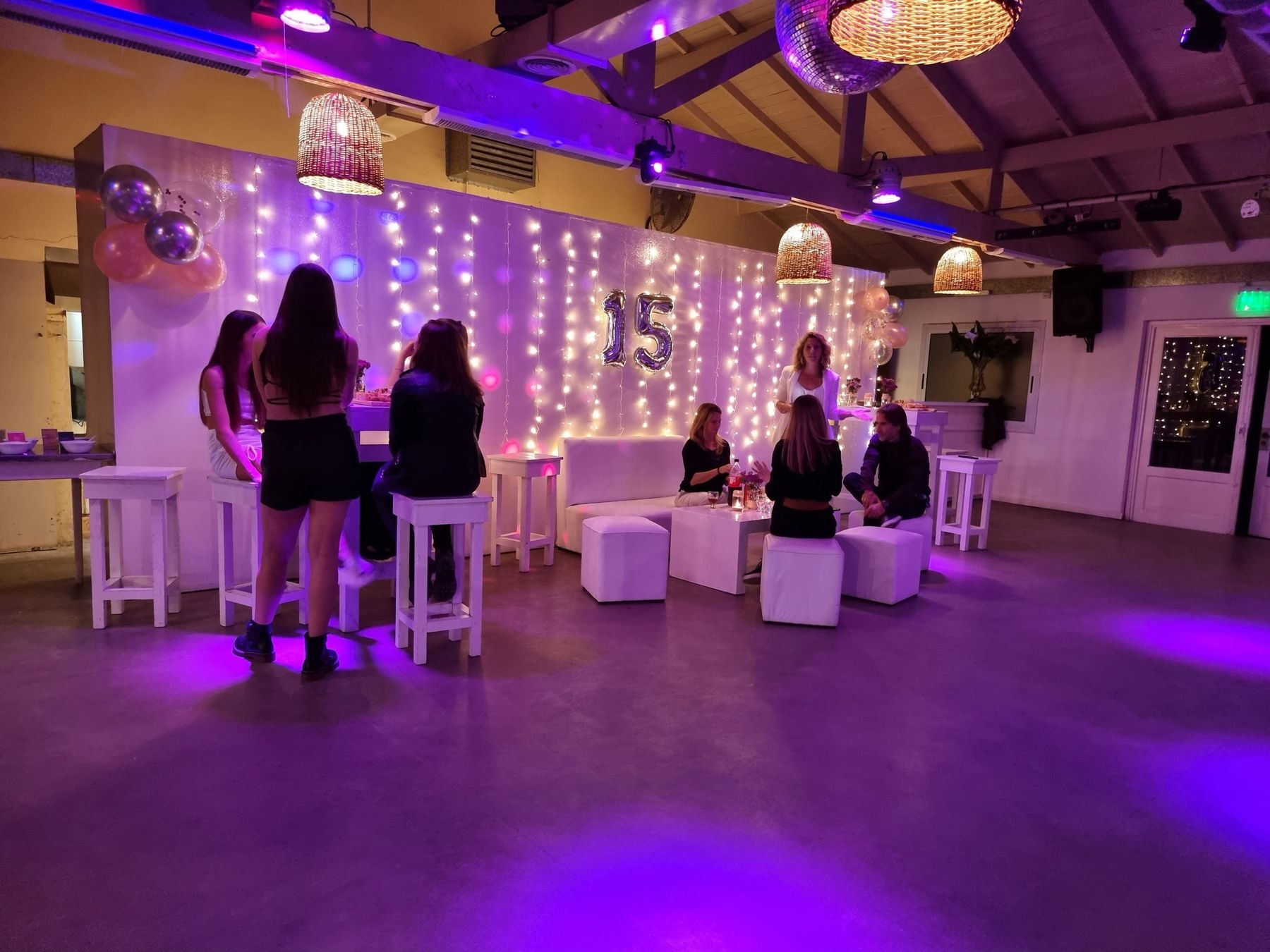 Fiesta de 15 con barras altas, cortina de luces y lámparas de mimbre