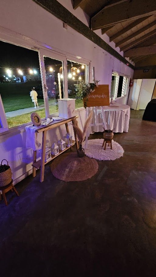 Rincón de bienvenida junto al ventanal con cartel, faroles y alfombras de yute
