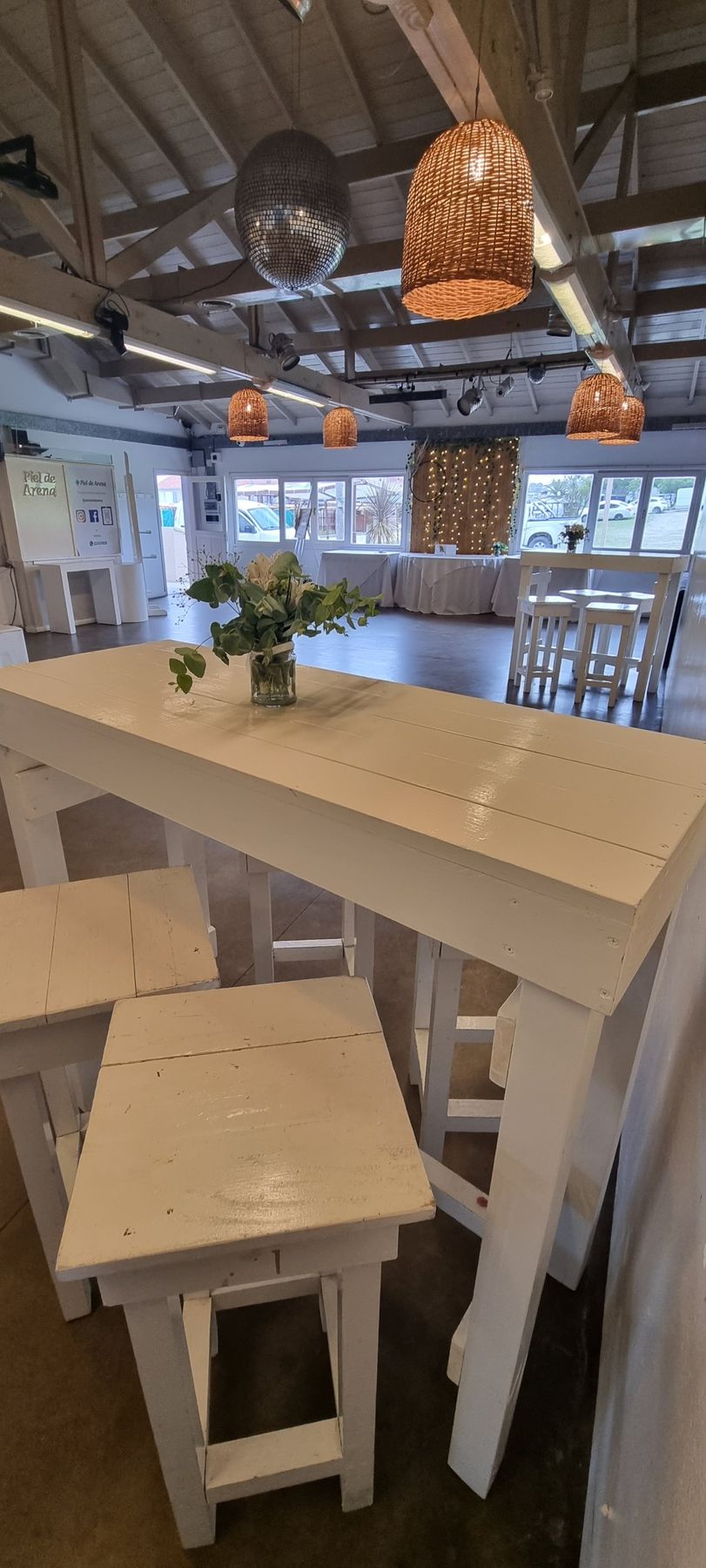 Barra alta blanca con banquetas, lámparas de mimbre y bola de espejos