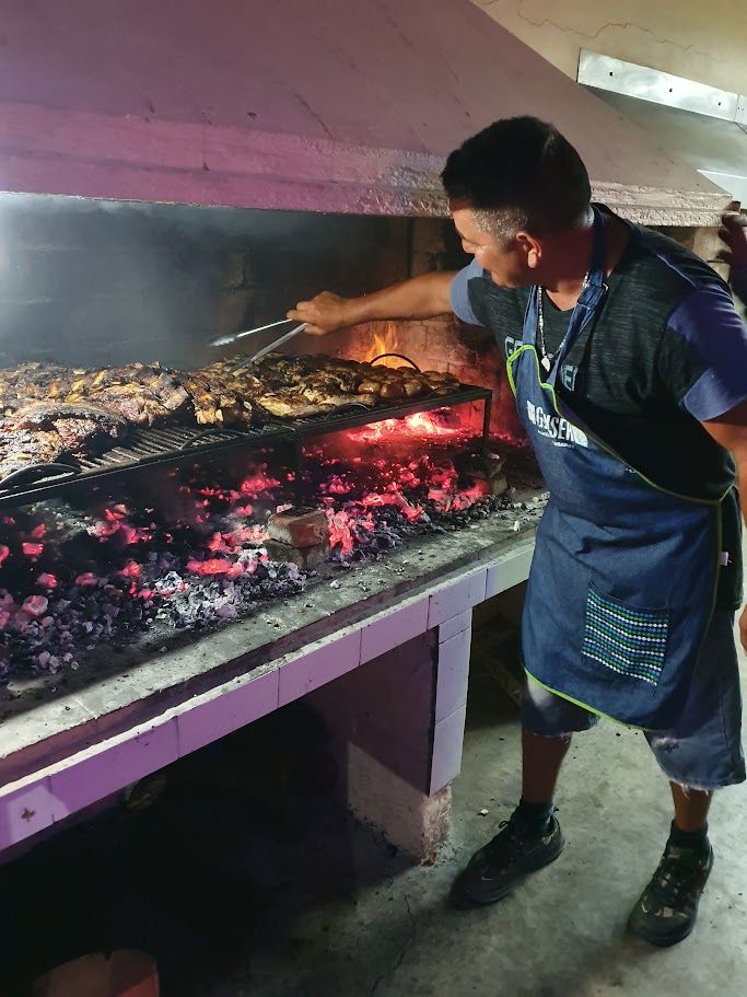 Asador preparando carne en la parrilla a leña