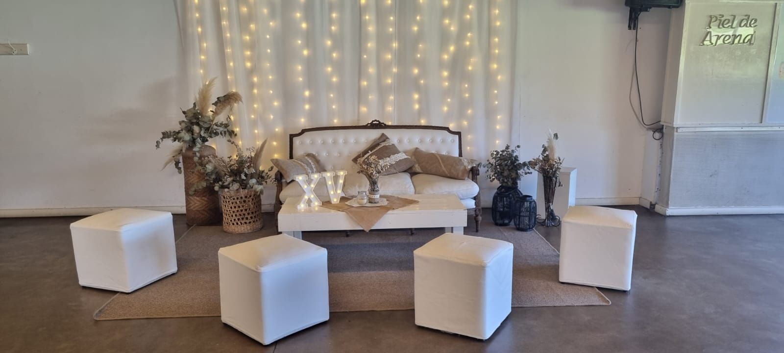 Living para fiesta de 15 con sillón capitoné, puffs blancos y cortina de luces