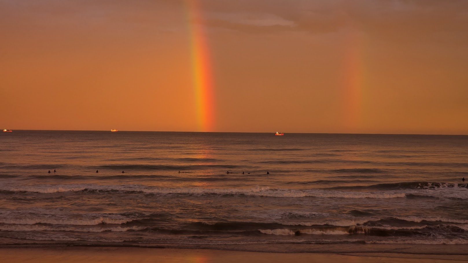 Vista al mar desde Piel de Arena al atardecer, con un arcoíris sobre el horizonte