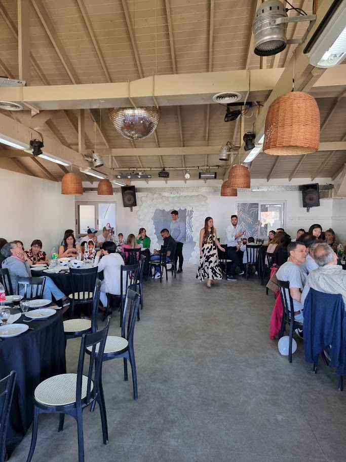 Almuerzo familiar en el salón con mesas de manteles negros y arco de globos