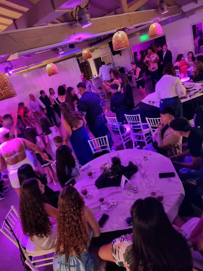 Fiesta en el salón con invitados bailando y mesas redondas con sillas Tiffany